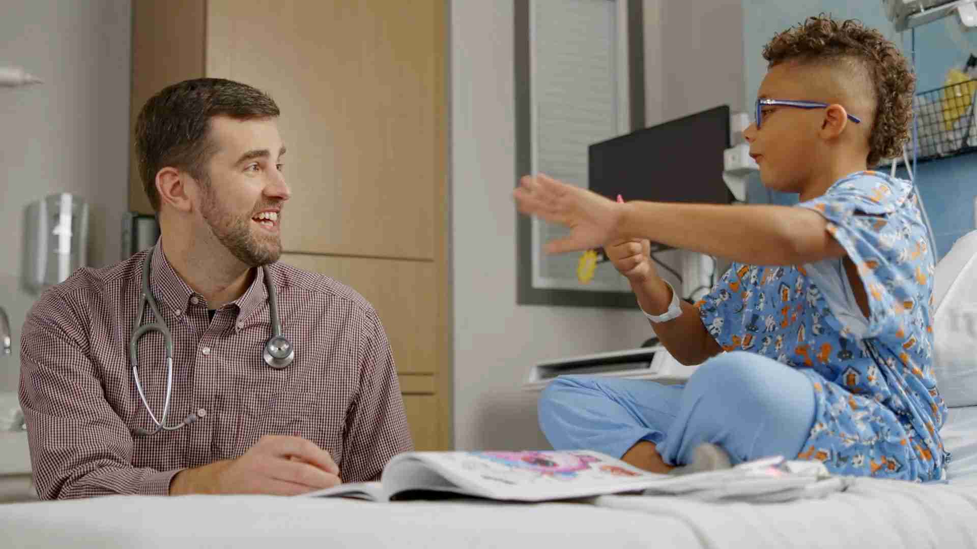 A doctor and a child talking in a hospital room.